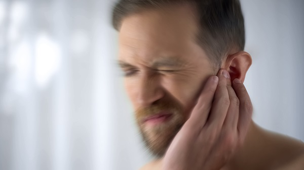 A man holds his ear in pain after suffering hearing loss from a car accident. 245201266