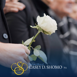 A mourner holds a white rose at a funeral following a wrongful death incident